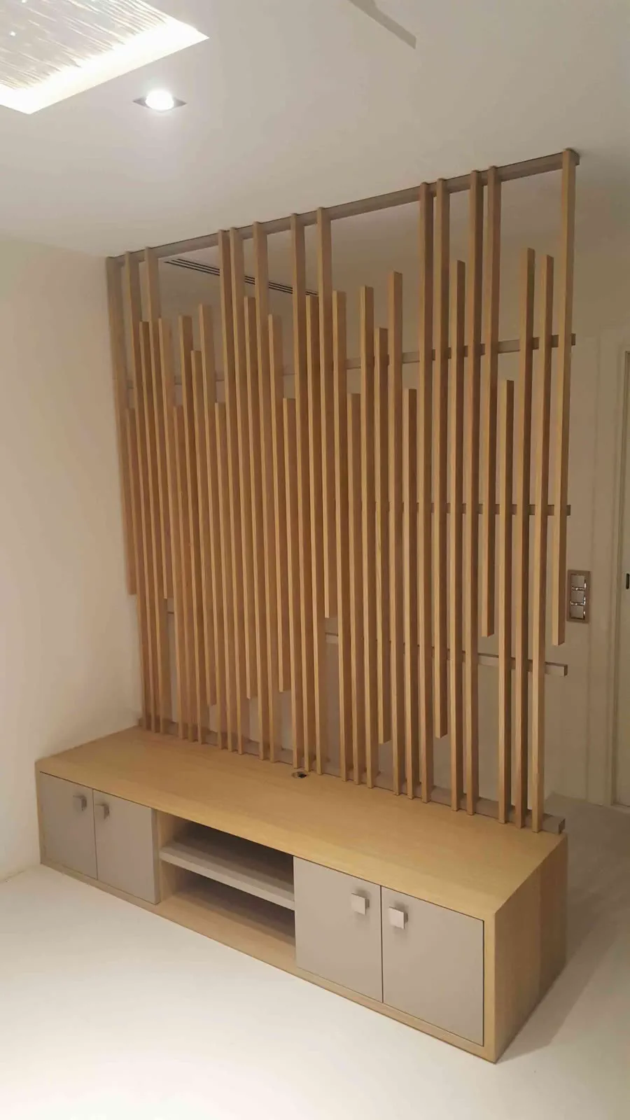 Entrée aménagée avec claustra vertical, banc et rangements en bois